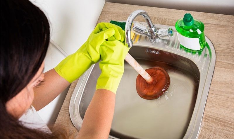 cropped picture of a woman trying to clean a drain