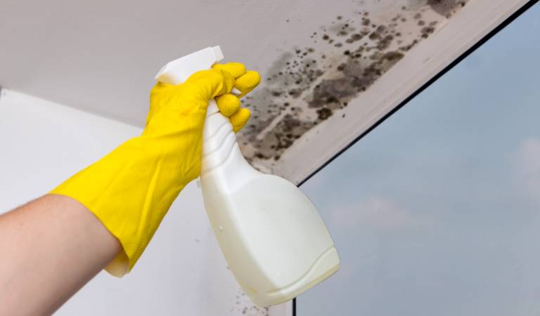 hand of a man in yellow gloves holding white bottle in his hand