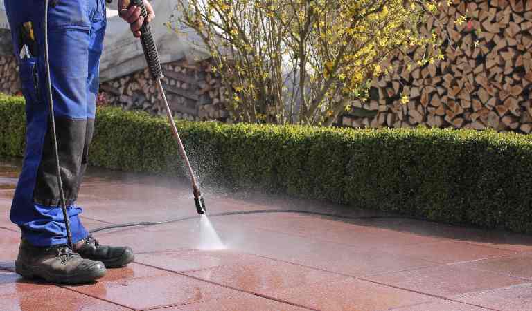 Man using pressure washer on tiles.