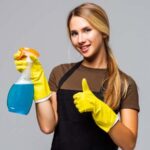 Woman in yellow gloves holding a bottle in her hand showing thumps up