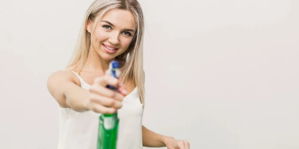 Lady holding a green bottle in her hand.
