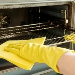Male hand with gloves cleaning oven