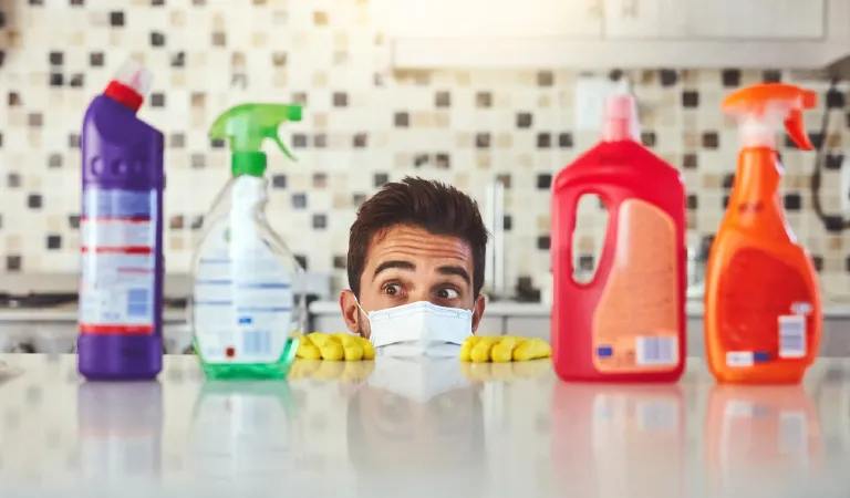 Man bottles and products by kitchen counter for cleaning peeking and cleaner with chemical liquid container spray