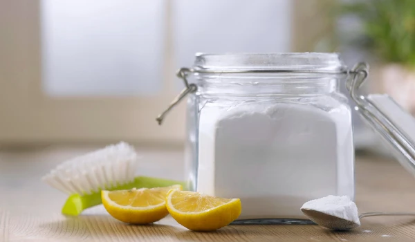 Closeup of baking soda powder next to vinegar toothbrush on wooden background