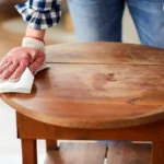 Woman cleaning old table surface with paper tissue