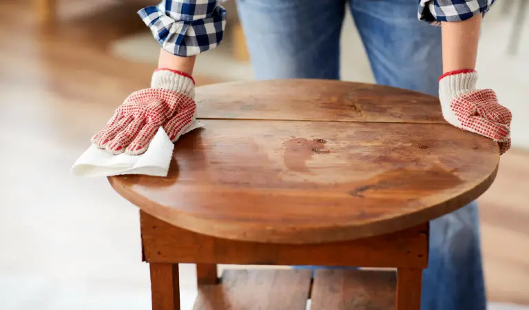 Woman cleaning old table surface with paper tissue